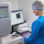 Woman laboratory assistant enters work data into the database, there is modern equipment in the laboratory
